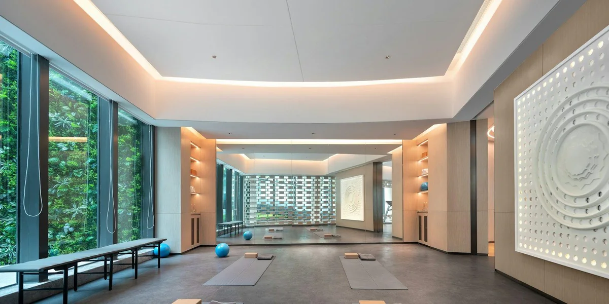 Estudio de yoga amplio con ventanales, esterillas en el suelo y luz cálida